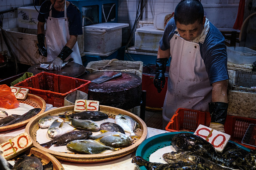 HongKong, China - November, 2019: Vendor preparing fish on food market in HongKong, China