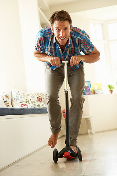 istock Man Riding Child's Scooter Indoors 177538367