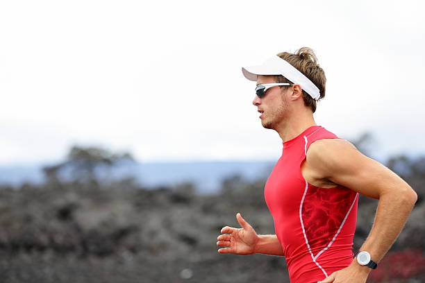 Running triathlon athlete "Running triathlon athlete man. Runner triathlete training for ironman on Hawaii. Young Male athlete running in red compression top on volcano in Kailua-Kona, Big Island, Hawaii. Click for more:" running jogging men human leg stock pictures, royalty-free photos & images