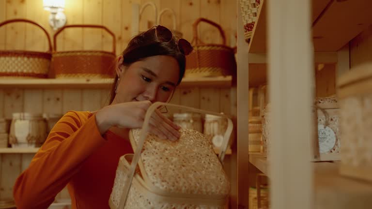 Young asian woman shopping for wicker baskets on shelves in a shopping mall.