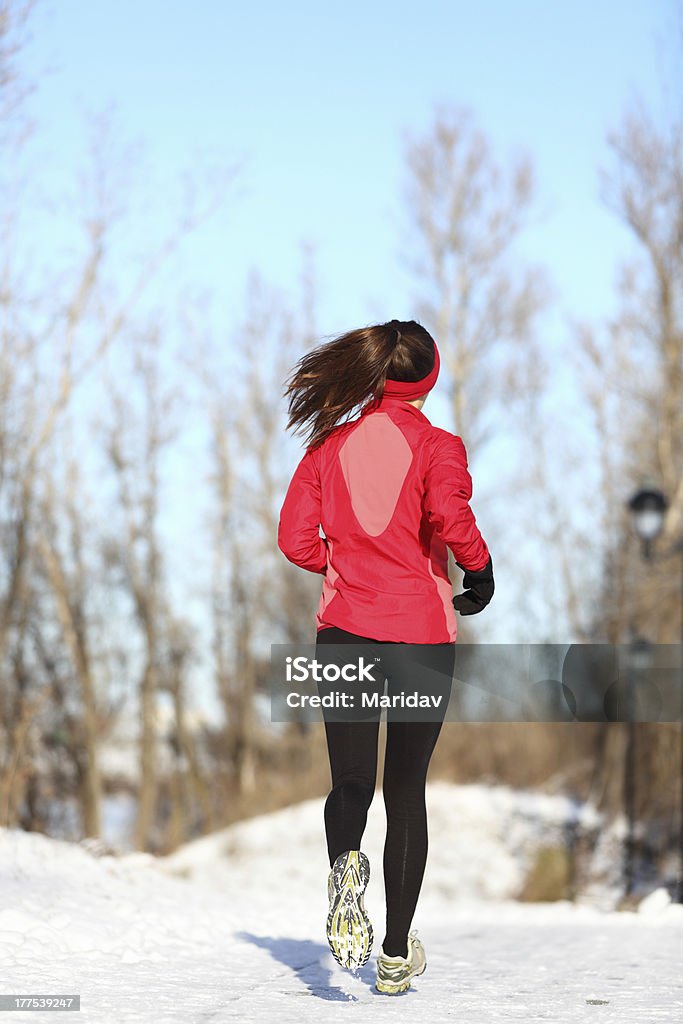Winter running woman in snow Winter running woman jogging in snow. Female runner in full body. Active lifestyle and wellness concept with young woman fitness model.Sport woman running in winter. One Woman Only Stock Photo