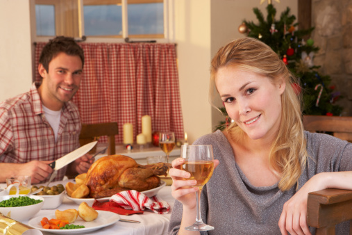Young couple having Christmas dinner smiling to camera