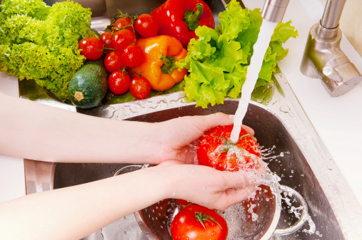 A woman washing fresh vegetables under the tap