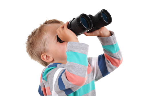 Young boy explorer searching with binoculars