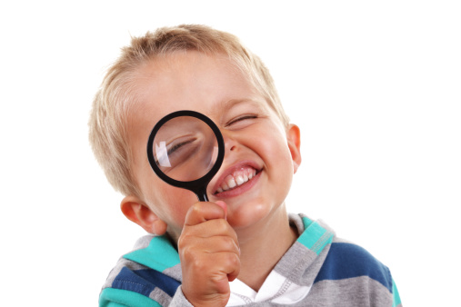 Little boy exploring with magnifying glass on white background