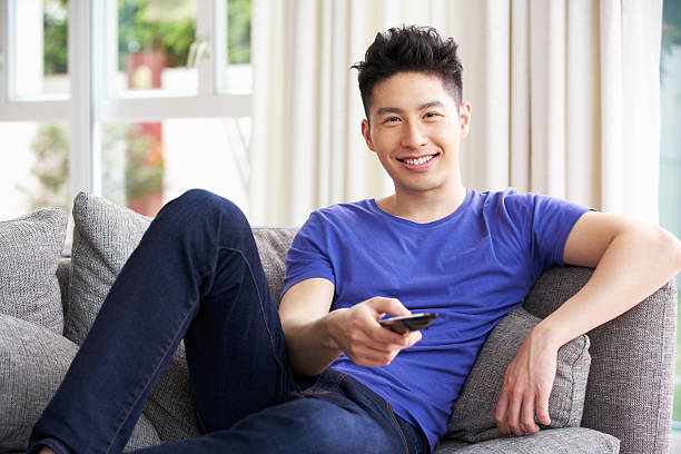 istock Young Chinese Man Watching TV On Sofa At Home 177543704