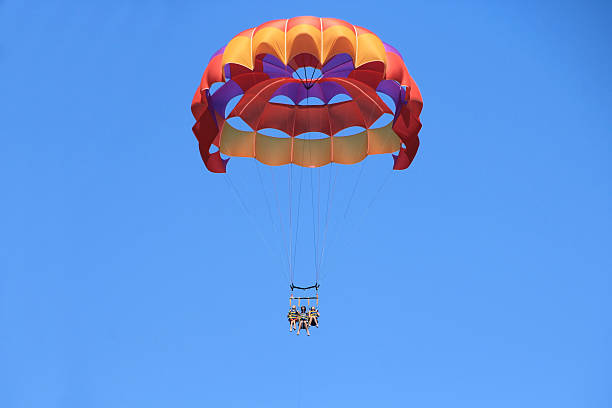 Happy Family Parasailing Father and Twin Daughters Parasailing Against a Blue Summer Sky. Soft focus on faces. parasailing stock pictures, royalty-free photos & images