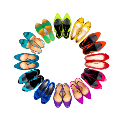 Set of multicolored female shoes arranged in circle on white background.