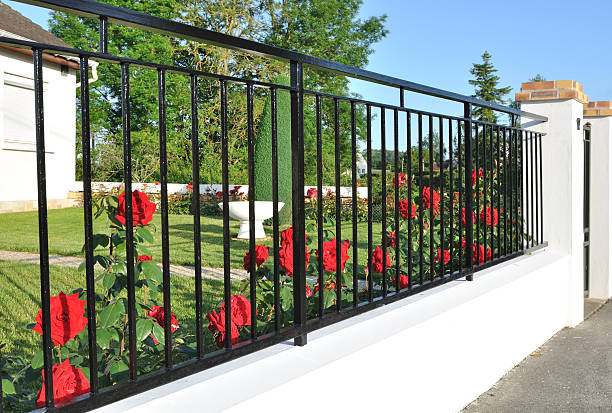 Closing flowered roses elegant black metal fence in front of red roses house railing stock pictures, royalty-free photos & images