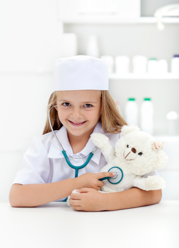 Little girl playing veterinary - examining her toy with stethoscope