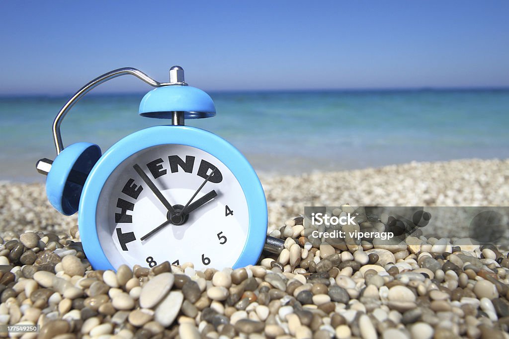Alarm clock on beach signaling end of summer End of summer concept. Alarm clock on the beach  Back to School Stock Photo
