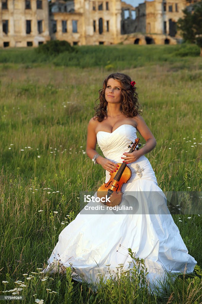 Uśmiechająca się Panna młoda z skrzypce w przód ruins - Zbiór zdjęć royalty-free (Biały)