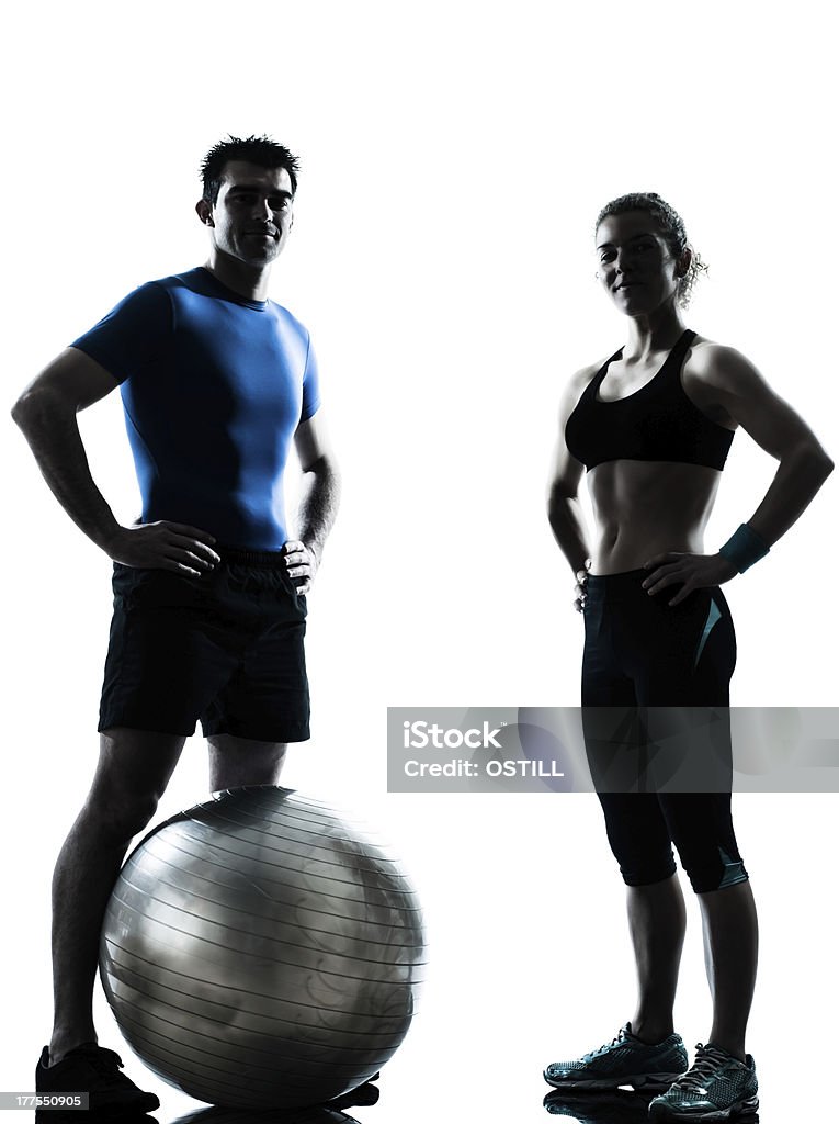 man woman exercising workout fitness ball one caucasian couple man woman personal trainer coach exercising fitness ball silhouette studio on white background In Silhouette Stock Photo