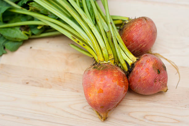 Freshly picked organic golden beets on a wooden cutting board.