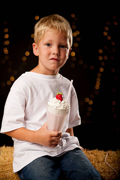 istock Young boy with milkshake sitting on hay bale. 177555385