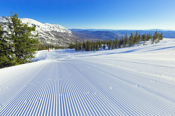 schnee samt und blauer himmel auf der skipiste auf dem mount green, skigebiet sheregesh. präparierte ski- und snowboardspur mit spuren von pistenraupen auf schnee. schöner sonniger wintertag für sport, freizeit - ski trace stock-fotos und bilder