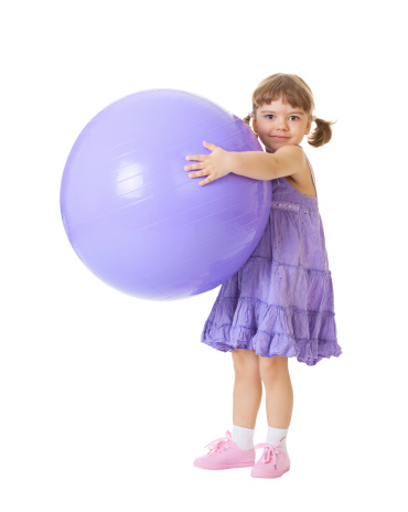 Little girl with a big purple ball isolated on white background