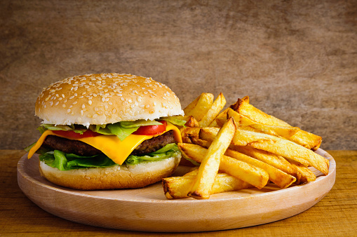 Fast food menu with hamburger and french fries on a wooden plate