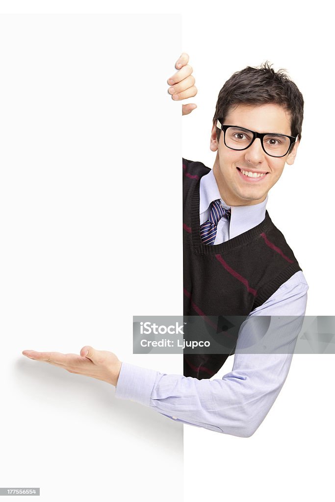 Smiling handsome male posing behind a panel Smiling handsome male posing behind a blank panel isolated on white background Behind Stock Photo