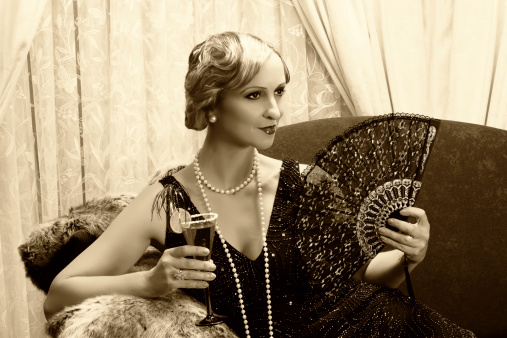 Sepia image of a vintage twenties lady with cocktail and lace fan