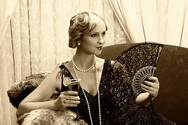 Sepia image of a vintage twenties lady with cocktail and lace fan