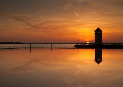 The sun sets over a seaside watch tower in the UK.