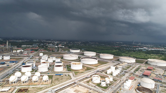 Aerial view of Oil and gas industry Refinery factory, and oil storage tank with dark cloud sky in the background