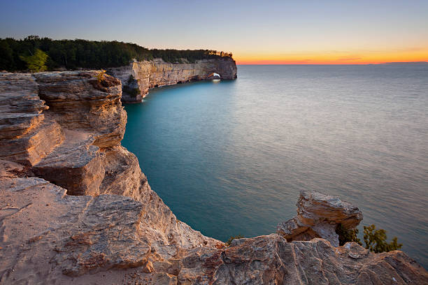 Wide shot of rocks looking over sea at sunset in Michigan stock photo