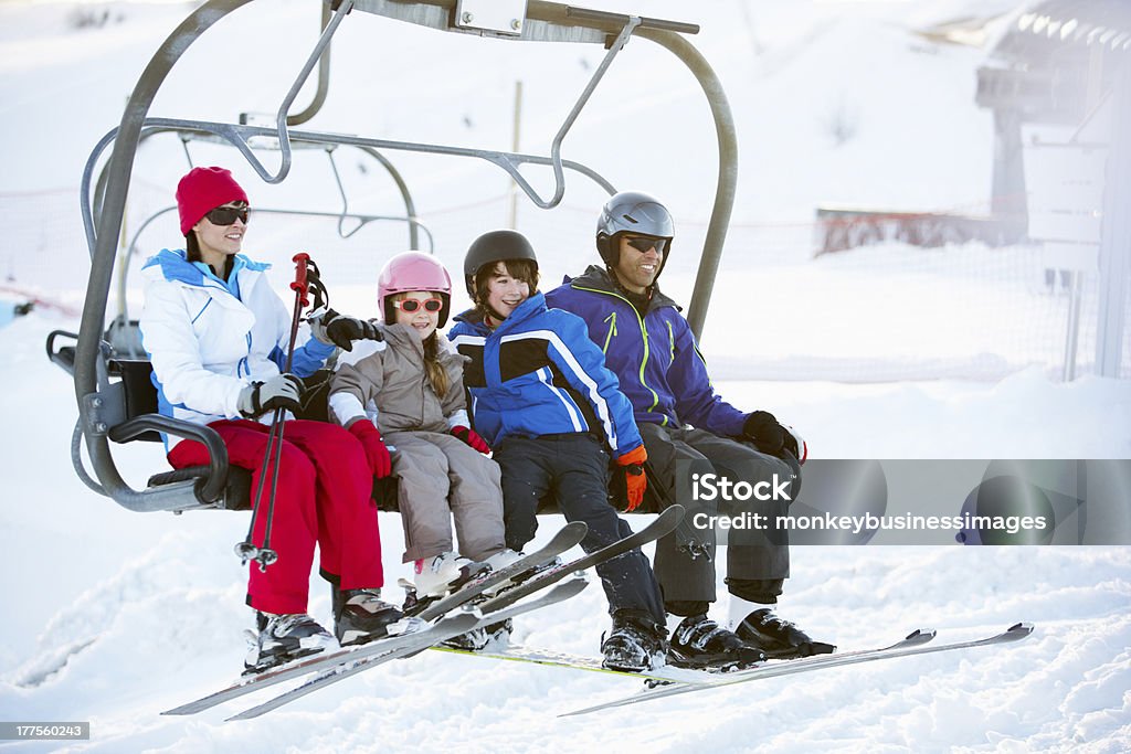 Family Getting Off Chair Lift On Ski Holiday In Mountains Family Getting Off Chair Lift On Ski Holiday In Mountains Wearing Ski Gear Family Stock Photo