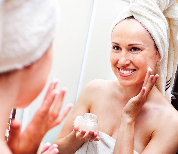 istock woman looking in mirror and applying cream 177561393