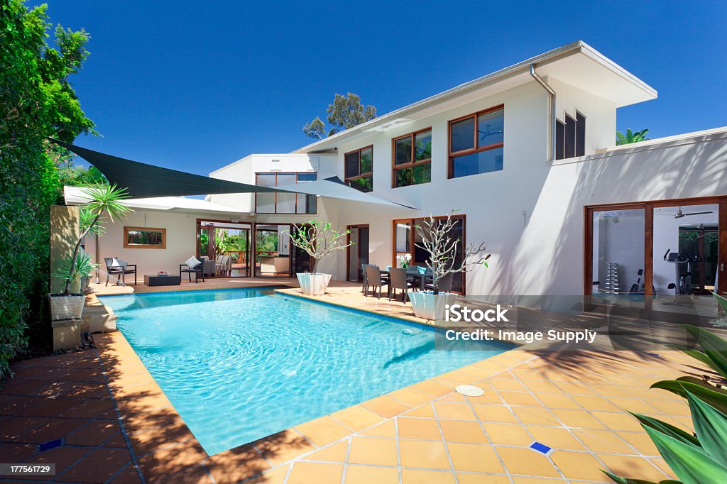 Rectangular swimming pool in back of a large white house Modern backyard with swimming pool and entertaining area in Australian mansion Swimming Pool Stock Photo