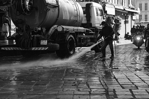 A worker seen using water to clean the road of Basantapur Durbar square early in the morning at Kathmandu, Nepal. As crowd increases at the day time, worker has to clean the road in the morning and as quickly as they can.