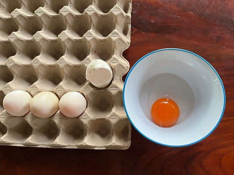 Pallet with white eggs and yolk egg on the bowl.