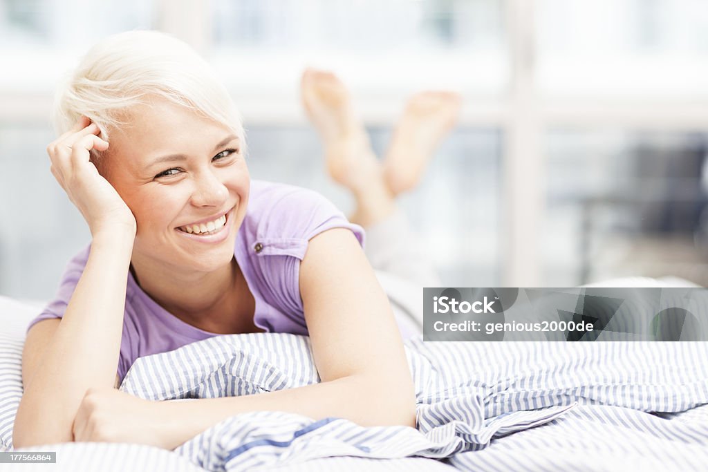 Wunderschöne blonde Frau posieren auf dem Bett, während lächelnd - Lizenzfrei Attraktive Frau Stock-Foto