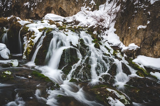 A small waterfall with a blanket of snow on top.