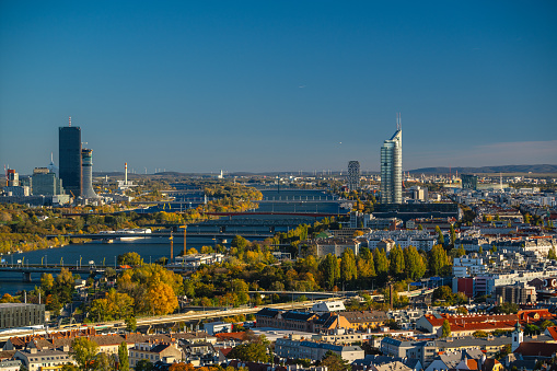 vienna city, capital of austria, with skyscrapers and many bridges over the danube river on sunny autumn day with clear blue sky and autumn colored trees