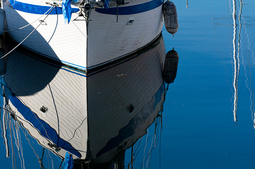 A crystal clear water reflection of the hull of a boat moored to a dock.