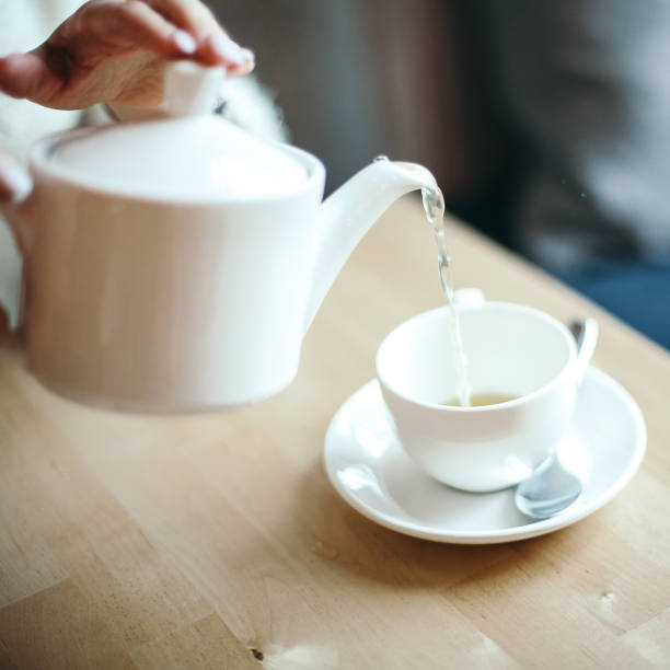 istock pour tea from a teapot into a white Cup, white kitchen utensils, cafe service concept, teapot with a white mug, aroma, taste, break, Breakfast 1775735823