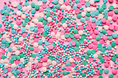 Multi-colored confectionery topping on a pink.