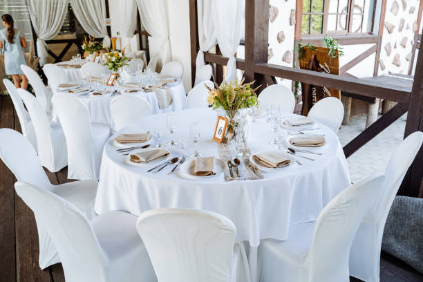 istock Serving a festive table, placing plates on the table, a Banquet table with a white tablecloth, preparing the dining table for the holiday, Cutlery is arranged according to etiquette. flowers on the table. 1775788228