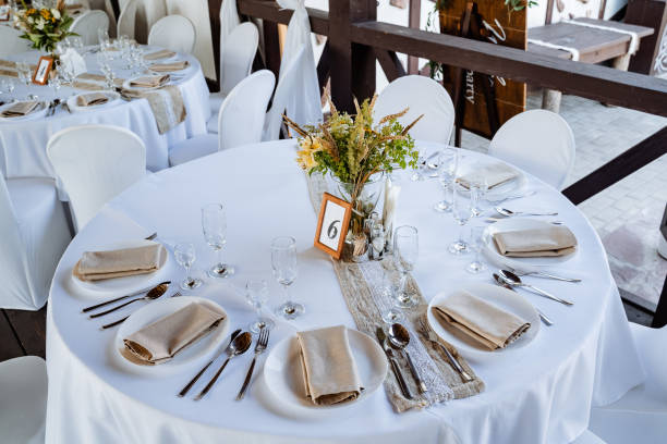 istock Serving a festive table, placing plates on the table, a Banquet table with a white tablecloth, preparing the dining table for the holiday, Cutlery is arranged according to etiquette. flowers on the table. 1775788242