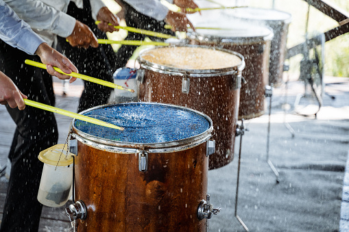 Drums stand in a row. drumsticks. drummers. splashes of water on the membrane