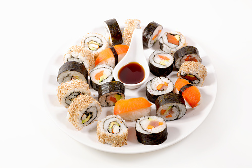 plate of sushi rolls and soy sauce isolated on white background