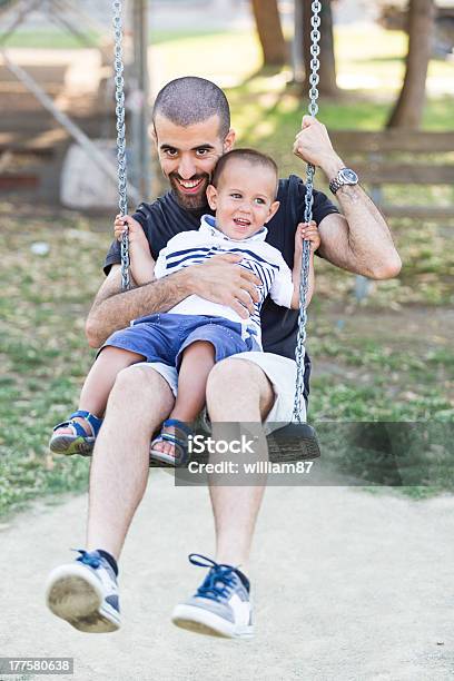 Little Boy Playing On Swing Con Padre O El Tío Foto de stock y más banco de imágenes de Adulto - Adulto, Aire libre, Columpio