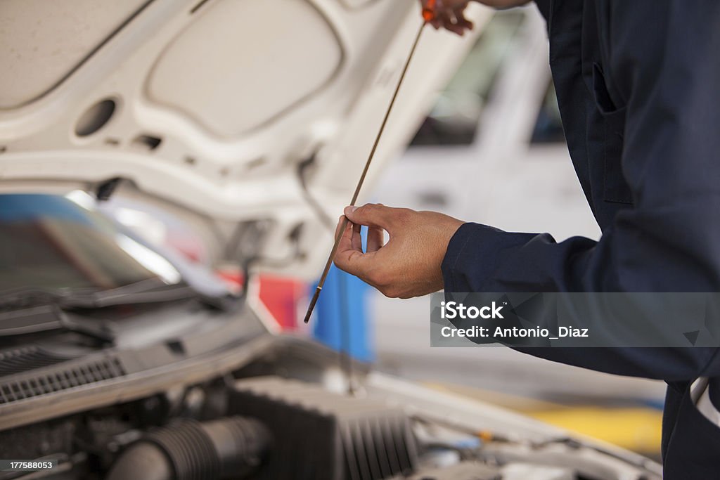 Checking oil levels of a car Closeup of a mechanic checking oil levels of a car at an auto shop Adult Stock Photo