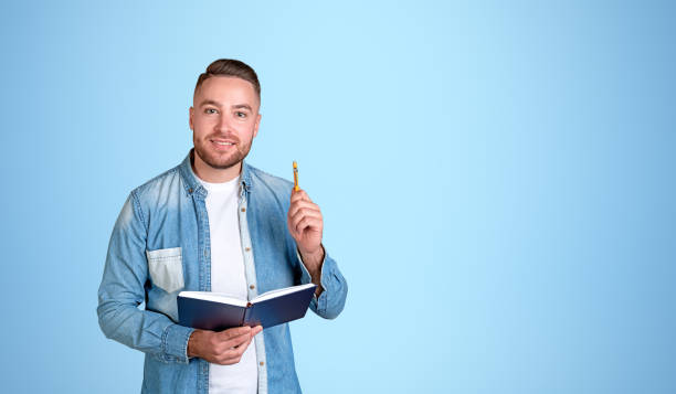 istock Cheerful man college student with notebook and pen, blue 1775886419