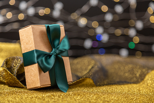 Christmas gift box or present against golden bokeh background. Holiday greeting card.