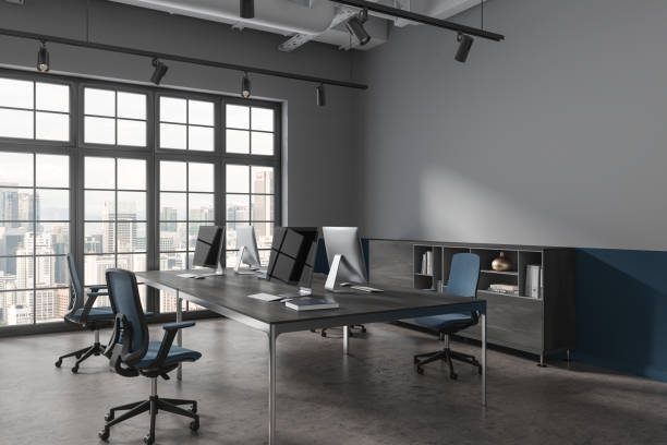 istock Dark office interior with pc monitors and sideboard, window. Mock up wall 1775899655