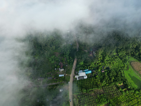 Aerial top view flying over mountains and rural villages in mist-shrouded morning.