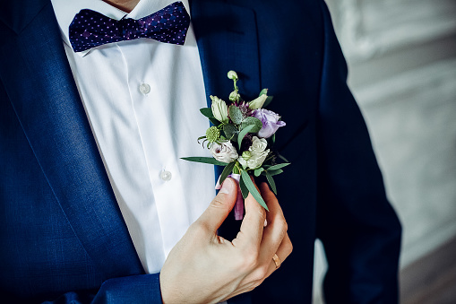 The groom corrects the bud on the jacket. The groom's wedding attribute. Tsvkat at the wedding. decoration bouquet in hand. Preparing for the wedding.